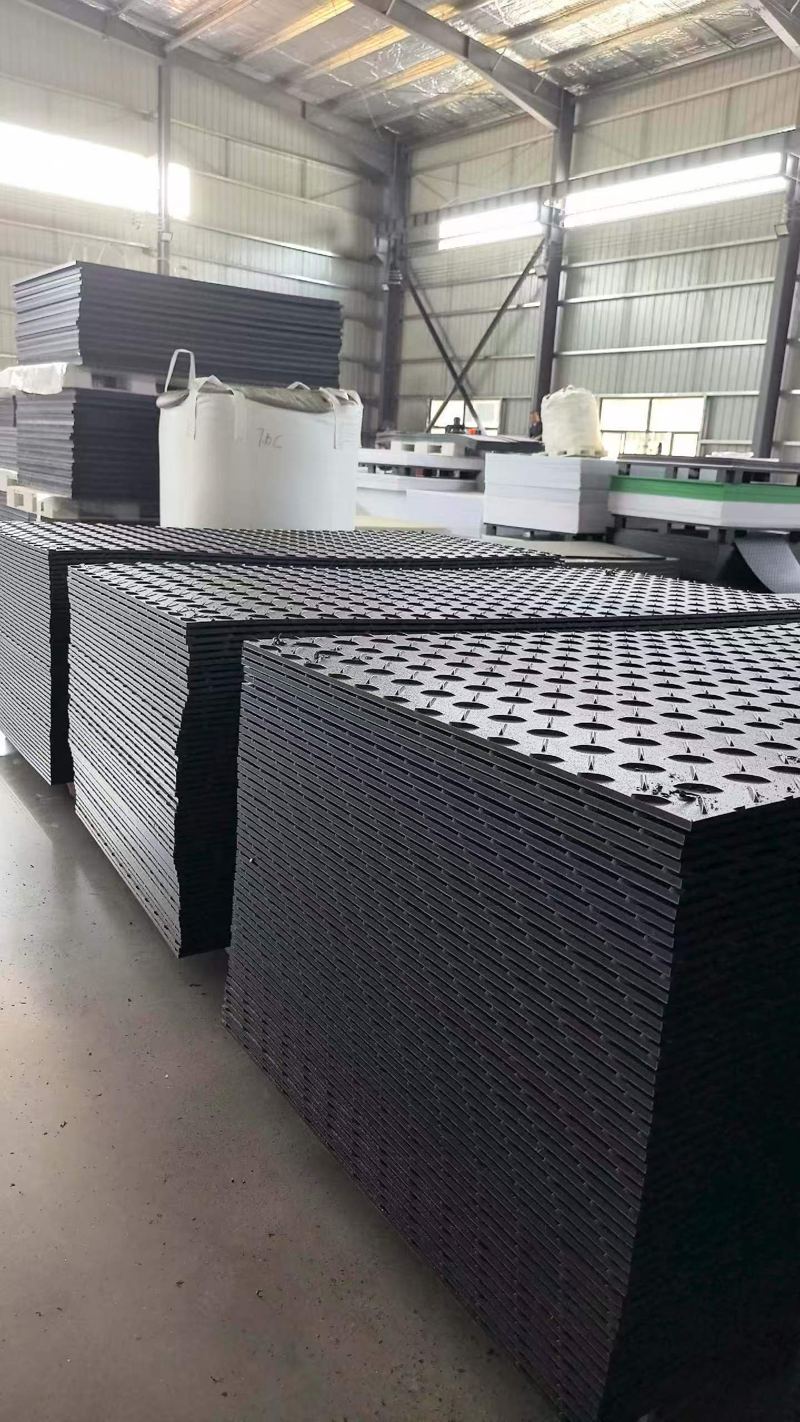Stacks of black HDPE ground protection mats in the factory